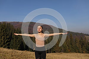 Young woman doing stretching exercises on nature in mountains. Sports girl practicing yoga pose in leggings. beautiful forest