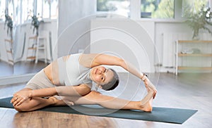 Young woman doing stretching Parivrtta Janu Sirsasana asana