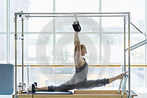 Young woman doing stretching on pilates bed.