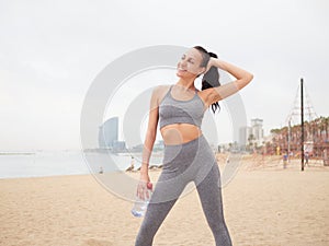 young woman doing stretching at Playa de la Barceloneta - Barcelona Spain. photo