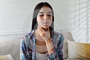 Young woman doing thyroid self examination at home