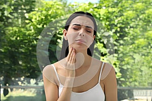 Young woman doing thyroid self examination near window