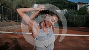 Young woman doing warm-up of upper body in stadium on sunny afternoon.