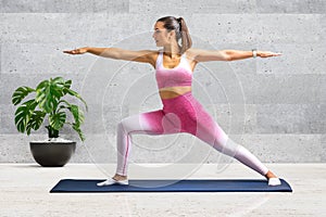 Young woman doing warrior yoga pose at home