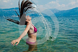 Mladá žena dělat voda vlasy kaluž v more 