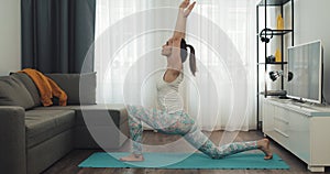 Young woman doing workout at home. Fitness girl doing yoga exercises on mat. Healthy and sport lifestyle.