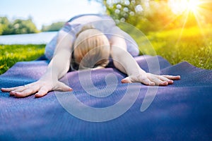 young woman doing yoga asana in park. girl stretching exercise in yoga position. happy and healthy woman sitting in