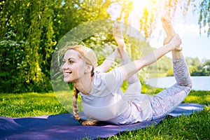 young woman doing yoga asana in park. girl stretching exercise in yoga position. happy and healthy woman sitting in