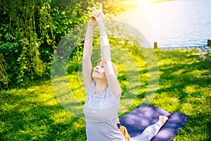 young woman doing yoga asana in park. girl stretching exercise in yoga position. happy and healthy woman sitting in