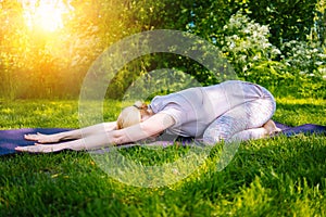 young woman doing yoga asana in park. girl stretching exercise in yoga position. happy and healthy woman sitting in