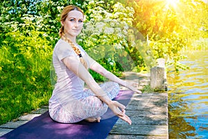 young woman doing yoga asana in park. girl stretching exercise in yoga position. happy and healthy woman sitting in