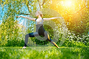 young woman doing yoga asana in park. girl stretching exercise in yoga position. happy and healthy woman sitting in