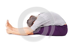 Young woman doing yoga asana seated forward bend Paschimottanasana