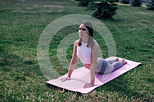 Young woman is doing yoga. Attractive woman in sports clothes lies on exercise mat in Cobra pose, performing