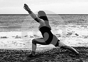 Young woman doing yoga at the beach in the early m