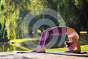 Young woman doing yoga in beautiful morning near lake