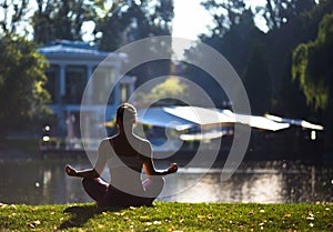 Young woman doing yoga in beautiful morning near lake