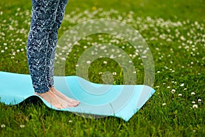 Young woman doing yoga exercise on green grass. face is not visible.