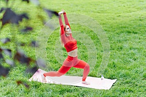 Young woman doing yoga exercise in green park