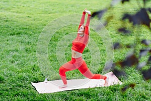 Young woman doing yoga exercise in green park