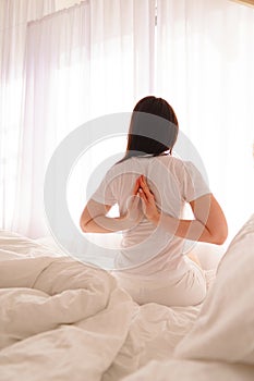 Young woman doing yoga exercise in her bed at home