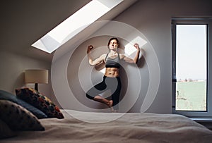 Young woman doing yoga exercise indoors in a bedroom. Copy space.