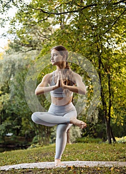 Young woman doing yoga exercise outdoor in the park, sport yoga concept