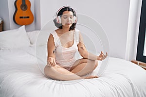 Young woman doing yoga exercise sitting on bed at bedroom