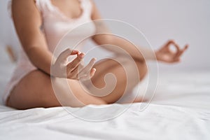 Young woman doing yoga exercise sitting on bed at bedroom