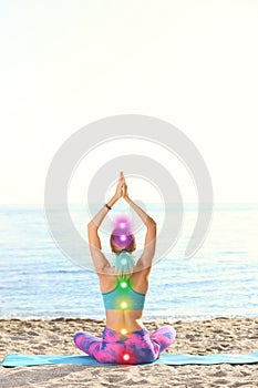 Young woman doing yoga exercises on beach