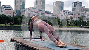 Young woman doing yoga exercises with city on background. purvottanasana