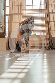 Young woman doing yoga exercises early in the morning. Meditates after sleep in a bright sunny room. Healthy lifestyle .sport