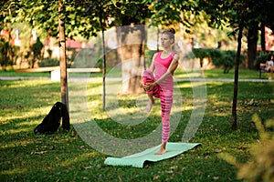 Young woman doing yoga exercises on the grass in a park
