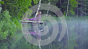 Young woman doing yoga exercises on the lake shore