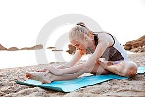 Young woman doing yoga exercises on mat outdoors