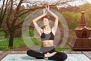 Young woman doing yoga exercises outdoors. Yoga meditation in park