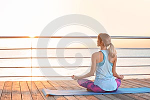 Young woman doing yoga exercises on pier