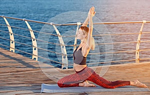 Young woman doing yoga exercises on pier