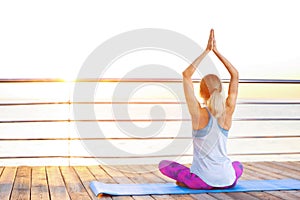 Young woman doing yoga exercises on pier