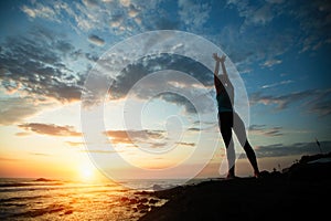 Young woman doing yoga exercises on the seashore