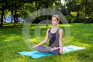 Young woman doing yoga exercises in the summer city park.