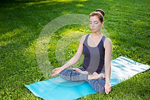 Young woman doing yoga exercises in the summer city park.