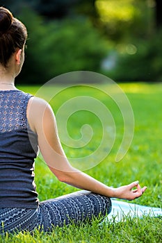 Young woman doing yoga exercises in the summer city park.
