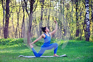 Young woman doing yoga exercises in the summer city park. Health lifestyle concept.