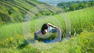 Young woman doing yoga in green summer meadow