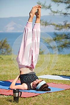 Young woman is doing yoga near lake