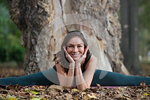 young woman doing yoga next to the tree