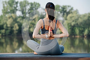 Young woman doing yoga outdoors in a beautiful spot on a riverside