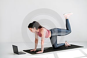 Young woman doing yoga or pilates donkey kick exercise with leg raise on mat