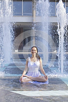 young woman doing yoga pose in city fountain